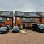 Modern houses with solar panels and parked cars.