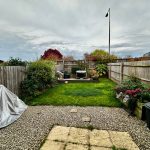 Peaceful garden with grass, plants, and wooden fencing.