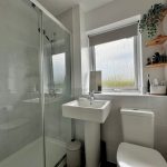 Modern bathroom with glass shower and white fixtures.