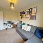 Living room with sofa, keyboard, and artwork on walls.