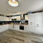 Modern white kitchen with wooden countertops.