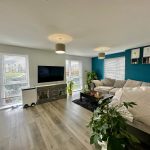 Modern living room with plants and grey furnishings.