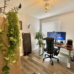 Modern home office with plants and computer setup.