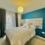 Modern bedroom with blue accent wall and double bed.