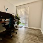 Modern home office with desk, chair, and plant.