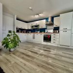 Modern kitchen with white cabinets and wooden floor.
