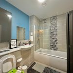 Modern bathroom with blue accent wall and bathtub.