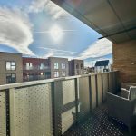 Sunny balcony overlooking modern buildings.