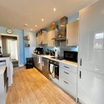 Modern kitchen with appliances and wooden flooring.