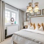 Elegant bedroom with framed pictures and large window.