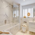 Modern marble bathroom with bathtub and vanity.