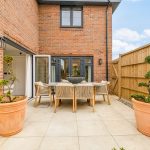 Modern patio with table, chairs, and potted plants.