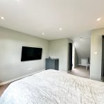 Modern bedroom with TV and grey decor.