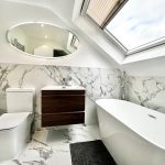 Modern bathroom with marble tiles and skylight.