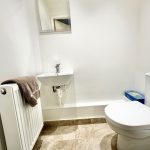 Compact bathroom with sink, toilet, and radiator.
