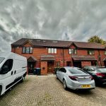 Brick terrace houses with parked cars on driveway.