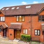 Red brick terraced house with brown doors and windows.