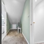 Narrow hallway with carpet and mint green walls.