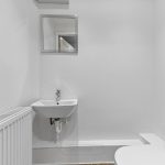 Minimalist white bathroom with sink and toilet