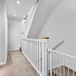 Carpeted hallway with staircase and safety gate.