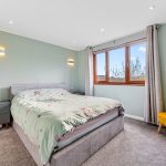 Modern bedroom with bed, window, and yellow chair.