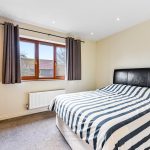 Modern bedroom with striped bedding and large window.