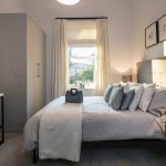 Modern bedroom with double bed and decorative pillows.