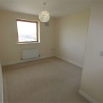 Empty beige room with window and light fixture.