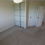 Empty room with carpet and wardrobe doors.