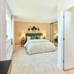 Modern bedroom with beige walls and green headboard.