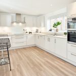Modern white kitchen with hardwood flooring.