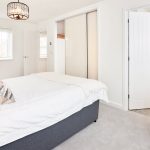 Modern bedroom with white bed and grey chair.