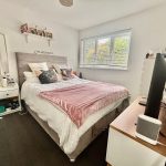 Cosy bedroom with double bed and pink duvet.