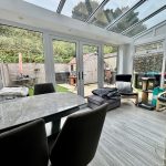 Modern conservatory with garden view and seating.