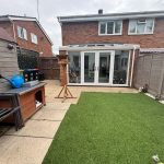 Backyard with artificial grass and conservatory.
