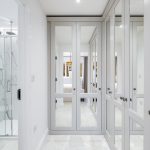 Modern bathroom with marble shower and mirrored wardrobes.