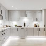 Modern white kitchen with sleek cabinets and lighting.