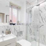 Modern bathroom with marble tiles and glass shower.