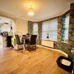 Dining room with wooden floors and floral wallpaper.