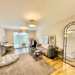 Spacious living room with modern decor and large mirror.