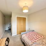 Cosy bedroom with double bed and wooden wardrobe.