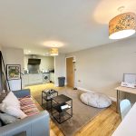 Modern living room with kitchen and desk area.