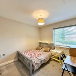 Bright bedroom with bed, desk, and window view.