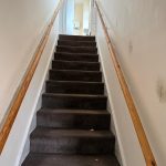 Carpeted staircase with wooden handrails in a hallway.