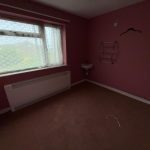 Empty bedroom with pink walls and a window.