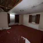 Damaged room with broken ceiling and debris.