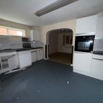 Empty kitchen with white cabinets and appliances.