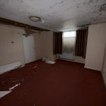 Room with damaged ceiling and fallen debris.