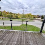 View from glass balcony overlooking park and street.