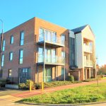 Modern apartment building with balconies and driveway.